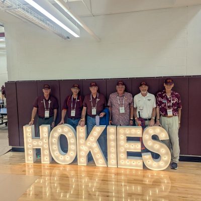 Alumni in front of Hokies sign